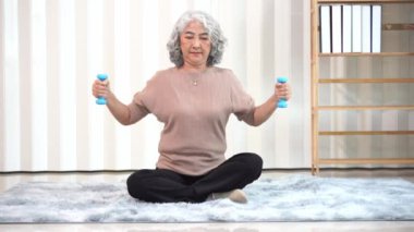 Spor elbiseli, yoga ve spor egzersizi yapan emekli Asyalı son sınıf öğrencisi bir kadın. Dairedeki oturma odasında dinlenmek için. Yaşlı kadın her gün egzersiz yaparak sağlığını koruyor.