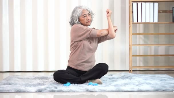 退休的亚洲老年妇女 穿着运动服 做瑜伽和健身锻炼 在公寓的客厅里休息 老年妇女通过每天锻炼来保持健康 — 图库视频影像