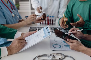 Masalardaki beyin fırtınası ve planlama doktorları, hemşireler ve bilgisayarlar birlikte çalışmanın çeşitliliğini gösteriyor. Tedavideki verileri analiz etmek için takım çalışması veya bir atölye