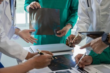 Masalardaki beyin fırtınası ve planlama doktorları, hemşireler ve bilgisayarlar birlikte çalışmanın çeşitliliğini gösteriyor. Tedavideki verileri analiz etmek için takım çalışması veya bir atölye