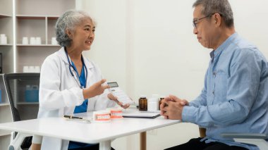 Kıdemli Asyalı kadın doktor diş ağrısı olan bir hastaya dişçi protezi gösteriyor. Muayenehanedeki diş muayenesinde tıbbi tedaviyi tartışıyorlar..