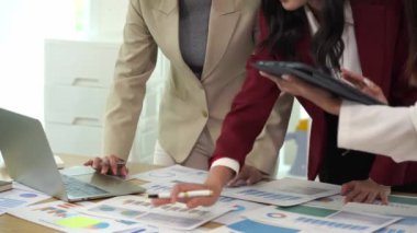 Genç Asyalı kadınların dizüstü bilgisayarları ve belgeleriyle bir araya gelerek proje mali raporları şirket işbirliği kavramını tartıştıkları bir iş toplantısı