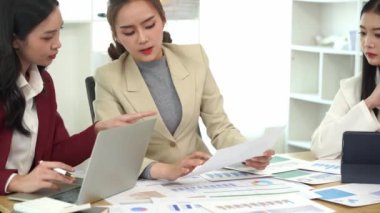 Genç Asyalı kadınların dizüstü bilgisayarları ve belgeleriyle bir araya gelerek proje mali raporları şirket işbirliği kavramını tartıştıkları bir iş toplantısı