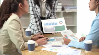 Genç Asyalı kadınların dizüstü bilgisayarları ve belgeleriyle bir araya gelerek proje mali raporları şirket işbirliği kavramını tartıştıkları bir iş toplantısı