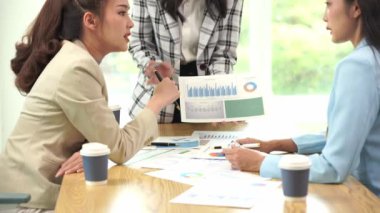 Genç Asyalı kadınların dizüstü bilgisayarları ve belgeleriyle bir araya gelerek proje mali raporları şirket işbirliği kavramını tartıştıkları bir iş toplantısı