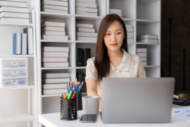 Dizüstü bilgisayarla çalışırken gülümseyen güzel Asyalı kadın muhasebeci ve finans, matematik, muhasebe raporları, istatistikler hakkında belgeler. ve araştırma fikirleri