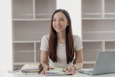 Asya 'lı iş kadını, finansal raporları analiz etmek için hesap makinesi dokümanlarıyla dizüstü bilgisayar pazarlama raporu kullanıyor.