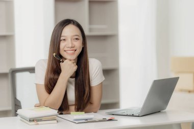 Asya 'lı iş kadını, finansal raporları analiz etmek için hesap makinesi dokümanlarıyla dizüstü bilgisayar pazarlama raporu kullanıyor.