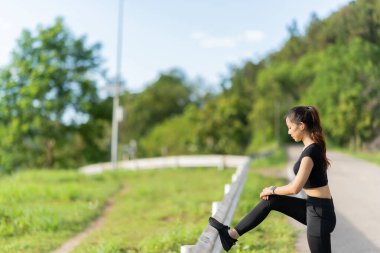 Sağlıklı genç bayan koşucu parkta koşmadan önce bacaklarını açar. Sağlık için egzersiz yapan, dışarıda koşan, insan ve yaşam tarzı, sağlık ve refah kavramı olan bir kadın. Parklarda ve dışarıda.