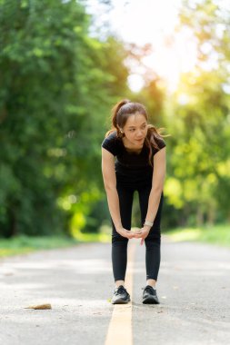 Sağlıklı genç bayan koşucu parkta koşmadan önce bacaklarını açar. Sağlık için egzersiz yapan, dışarıda koşan, insan ve yaşam tarzı, sağlık ve refah kavramı olan bir kadın. Parklarda ve dışarıda.