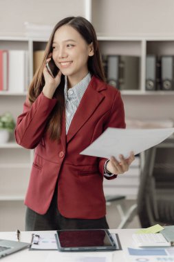 Asya 'lı iş kadını, finansal raporları analiz etmek için hesap makinesi dokümanlarıyla dizüstü bilgisayar pazarlama raporu kullanıyor.