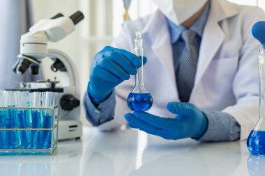 Kimya laboratuvarında ilaç araştırması yapan bilim adamları sıvı test analizi için cam tüpler, deney tüpleri ve mikroskoplar kullanıyorlar. Yakın plan fotoğraflar.