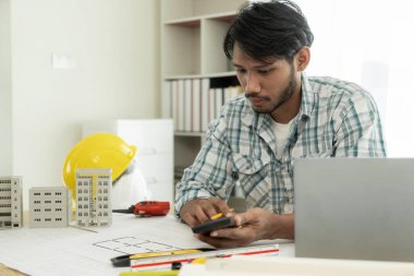 Kat planlarını inceleyen mimarlar, gayrimenkul inşaatı ile ilgili belgelerle çalışan ciddi inşaat mühendisleri ve profesyonel ustabaşı.: