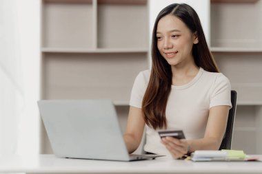 Finansal analizde çalışan Asyalı iş kadını. Masadaki mali ve muhasebe belgelerini hesaplıyor, notlar yazıyor ve gelir ve giderleri hesaplıyor..