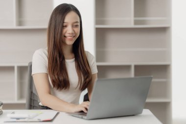 Ofisteki masada mali belgeler üzerinde çalışan iş kadını notlar yazıyor ve gelir ve giderleri hesaplıyor.
