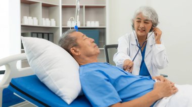 Üst düzey Asyalı erkek hasta yıllık muayenesi için doktoru ziyaret ediyor. Yaşlılara bakmakla görevli bakıcılar, yataktaki hastanelere, ilaçlara, sağlık hizmetlerine ve hayat sigortasına yardım ederler.