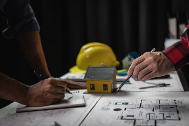 Mühendislerle ya da mimarlarla ortaklar ve mekanda modeller ve planlar yaratmak için mühendislik araçlarıyla çalıştıkları projeler için bir araya gelmek. Yakın plan resimler.