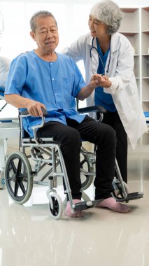 Yaşlı Asyalı bir adam, kıdemli bir kadın terapist hemşirenin desteğiyle fizik tedavi görüyor. Yaşlı adam evde bakım ve sağlık hizmetleri konseptinde hasta için elastik bant kullanıyor..