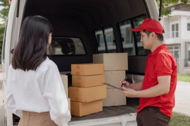 Kırmızı elbiseli genç kurye karton bir paket kutusu tutuyor ve kadınlar paketleri evden, online alışveriş ve mal teslimatından almak için cep telefonuyla para transfer ediyorlar..