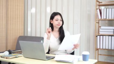 Evinde dizüstü bilgisayarlı finansal belgelerle çalışan Asyalı iş kadını pazarlamayı analiz ediyor, aylık muhasebe ve çizelgeler yapıyor. Ofiste. Evde çalış..
