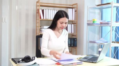 Evinde dizüstü bilgisayarlı finansal belgelerle çalışan Asyalı iş kadını pazarlamayı analiz ediyor, aylık muhasebe ve çizelgeler yapıyor. Ofiste. Evde çalış..