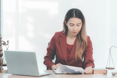 Kadın avukat ya da yargıç belgeleri ya da sözleşmeleri kontrol ediyor ve deftere notlar alıyor, hukuk bürosunda çekiç ve skalayla çalışıyor,.