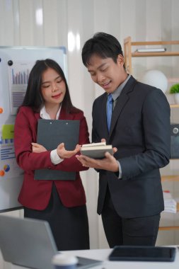 Yatırım işbirliği sunan Asyalı işadamlarının konferans odasında iş verileri grafikleri, yatırım projeleri ve stratejik planlamayı modern ofisteki tablet bilgisayarlarla tartışan