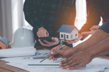 Mühendisler planların tasarlanmasına ve yapısal analizler üzerinde birlikte çalışmalarına yardım ediyorlar. Mimar İki mühendis mimari yapı taslaklarının planlarına işaret ediyor. Yakın plan resimler.