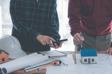 Mühendisler planların tasarlanmasına ve yapısal analizler üzerinde birlikte çalışmalarına yardım ediyorlar. Mimar İki mühendis mimari yapı taslaklarının planlarına işaret ediyor. Yakın plan resimler.