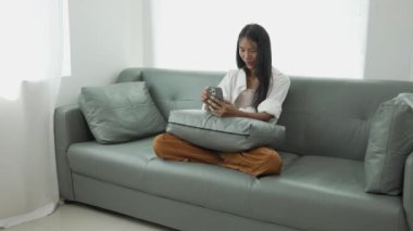 Akıllı telefon kullanan, internetten ödeme yapan, evden alışveriş yapan, e-ticaret yapan, internet bankacılığı yapan, hızlı para transferini seven, elektronik mağaza konseptini kullanan gülümseyen genç bir kadın..