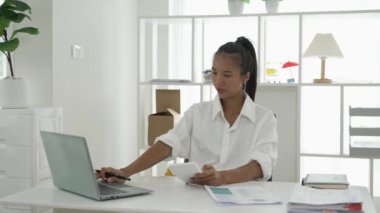 Genç Asyalı iş kadını iş prensiplerini hesaplamak için hesap makinesi kullanıyor. Yıllık mali raporun hazırlanması, hesap makinesinden alınan denetim sonuçları Gelir beyan edilen vergi oranını sayın.