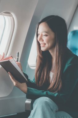 Uçuş, seyahat ve turizm konularında pencere kenarında çalışan Asyalı iş kadını, laptopla uçuş sırasında uçak kabininde çalışan başarılı Asyalı kadın.