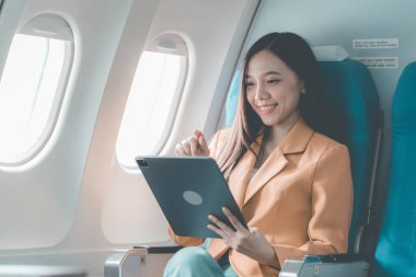 Uçuş, seyahat ve turizm konularında pencere kenarında çalışan Asyalı iş kadını, laptopla uçuş sırasında uçak kabininde çalışan başarılı Asyalı kadın.