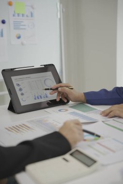 Proje planlarını ve mali sonuçları iş toplantılarında ya da seminerde tartışan iş adamlarına yakın çekim. Belgeler arasında mali veya pazarlama rakamları, grafikler ve grafikler yer alıyor.