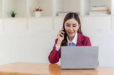 Ofisteki iş kadınları çevrimiçi mesajlar göndermek ve müşterilerle konuşmak için akıllı telefonlar kullanırlar ve internet üzerinden finansal iş yapmak, müşterileri tartışmak ve iletişime geçmek için dizüstü bilgisayarlar kullanırlar..