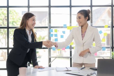 İş görüşmesi için el ele tutuşan muhabir. Anlaşmayı selamlama. İki mutlu Asyalı iş kadını el ele tutuşup başarılı iş anlaşmalarını tebrik ediyor..