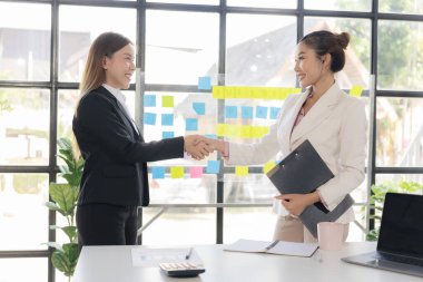 İş görüşmesi için el ele tutuşan muhabir. Anlaşmayı selamlama. İki mutlu Asyalı iş kadını el ele tutuşup başarılı iş anlaşmalarını tebrik ediyor..
