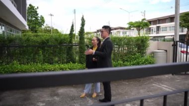 Asyalı emlak işadamı konut projesini teftiş ediyor. Genç bir çift ev inşaatının planını tartışıyor ve inceliyor..