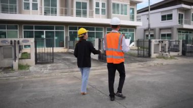 Asyalı emlak işadamı konut projesini teftiş ediyor. Genç bir çift ev inşaatının planını tartışıyor ve inceliyor..
