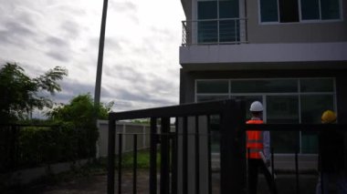 Asyalı emlak işadamı konut projesini teftiş ediyor. Genç bir çift ev inşaatının planını tartışıyor ve inceliyor..