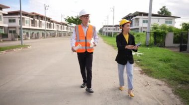 Asyalı emlak işadamı konut projesini teftiş ediyor. Genç bir çift ev inşaatının planını tartışıyor ve inceliyor..