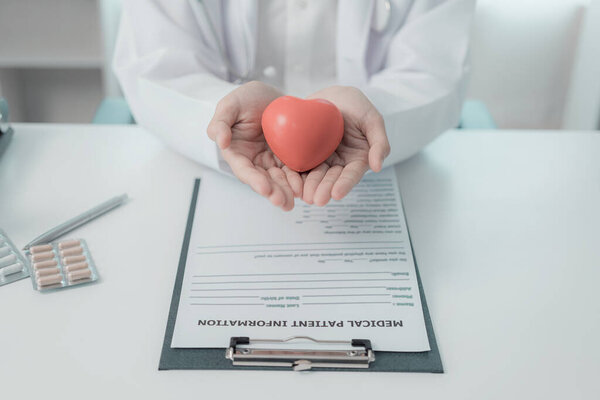 Врач в белом халате с красной моделью сердца в руках, концепция болезни сердца, крупным планом.