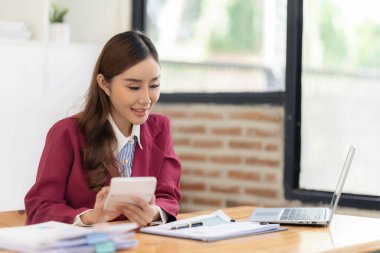 İş yerindeki bilgisayar ve mali belgeleri kullanarak iş verilerini hesaplayan Asyalı kadın çalışanlar, harcamalardaki muhasebe belgelerini kontrol ediyorlar. Finansal muhasebe kavramı.