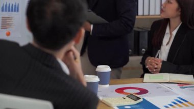 Bir grup Asyalı işadamı şirket bütçe toplantısı sırasında iş arkadaşlarına maliyet analizi grafikleri sundu. yakın çekim videosu