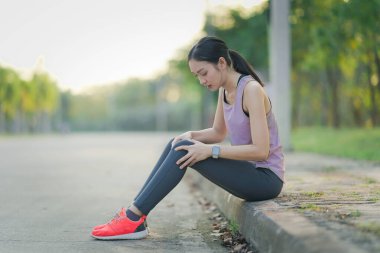 Asyalı kadının dizinde ve bacağında ağrı, spor sakatlığı, dışarıda egzersiz yaparken dizinde ağrı, kadın koşucu sakatlığı var.