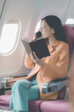 Uçak camındaki Asyalı kadın akıllı telefonla konuşurken cep telefonu kullanıyor. Bir insan işi hakkında konuşuyor..