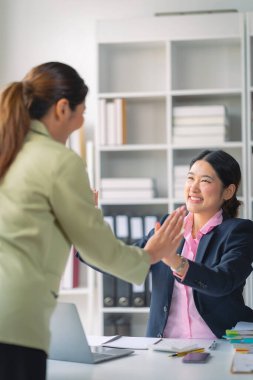 Ticari veri analizinde finansal veri grafik belgeleri ve dizüstü bilgisayarlarla çalışan iki başarılı Asyalı iş kadını.