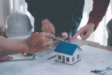 Mühendis ve mimarlardan oluşan bir ekip çalışma, planlama, ölçüm şemaları, inşaat alanındaki binaların planları, ofiste sıkı şapka giyen bir grup profesyonel mühendis.