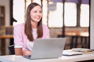Masada oturmuş gülümseyen, finansal grafikleri ve şirket hesaplarıyla ilgili önemli belgeleri okuyan güzel profesyonel bir kadın..