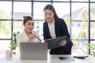İki kadın konuşur, tartışır, yeni proje fikirleri üzerinde çalışır. Başarı sağlamak için pazarlama planlarını ve iş yatırımlarını analiz edin.